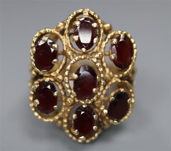 A 14k yellow metal and seven stone garnet set cluster dress ring, size L,